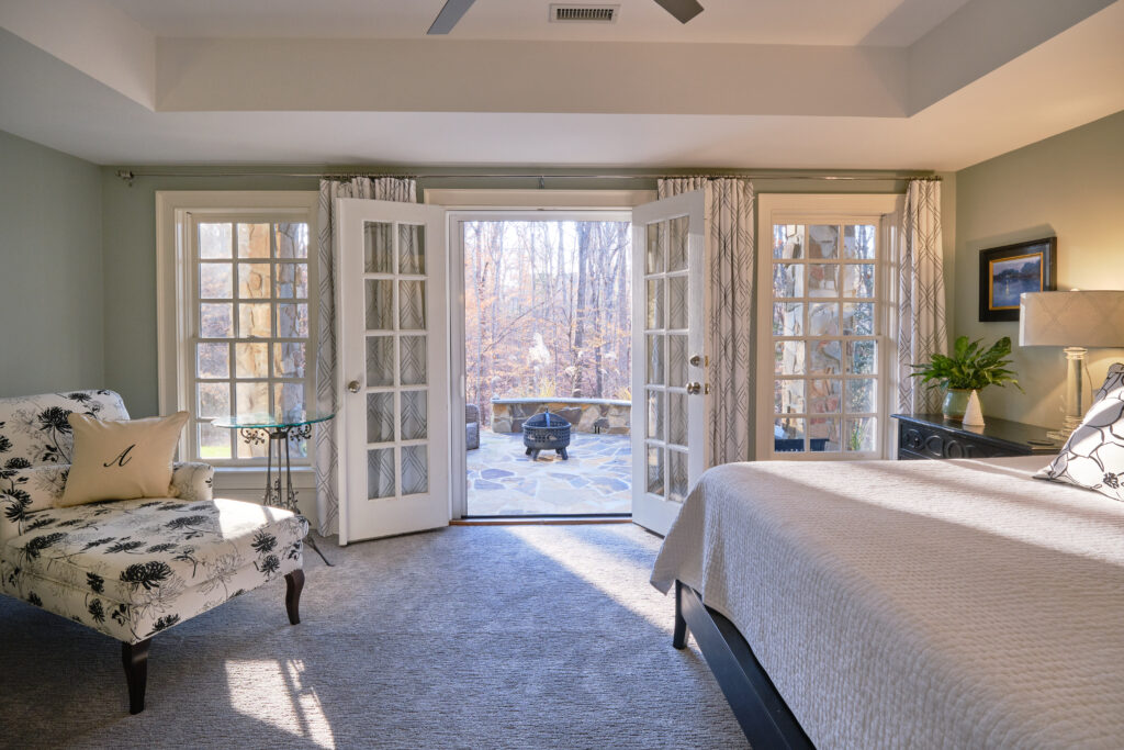 stunning bedroom opens up to a large backyard space with french doors in a luxury home remodel in wake county