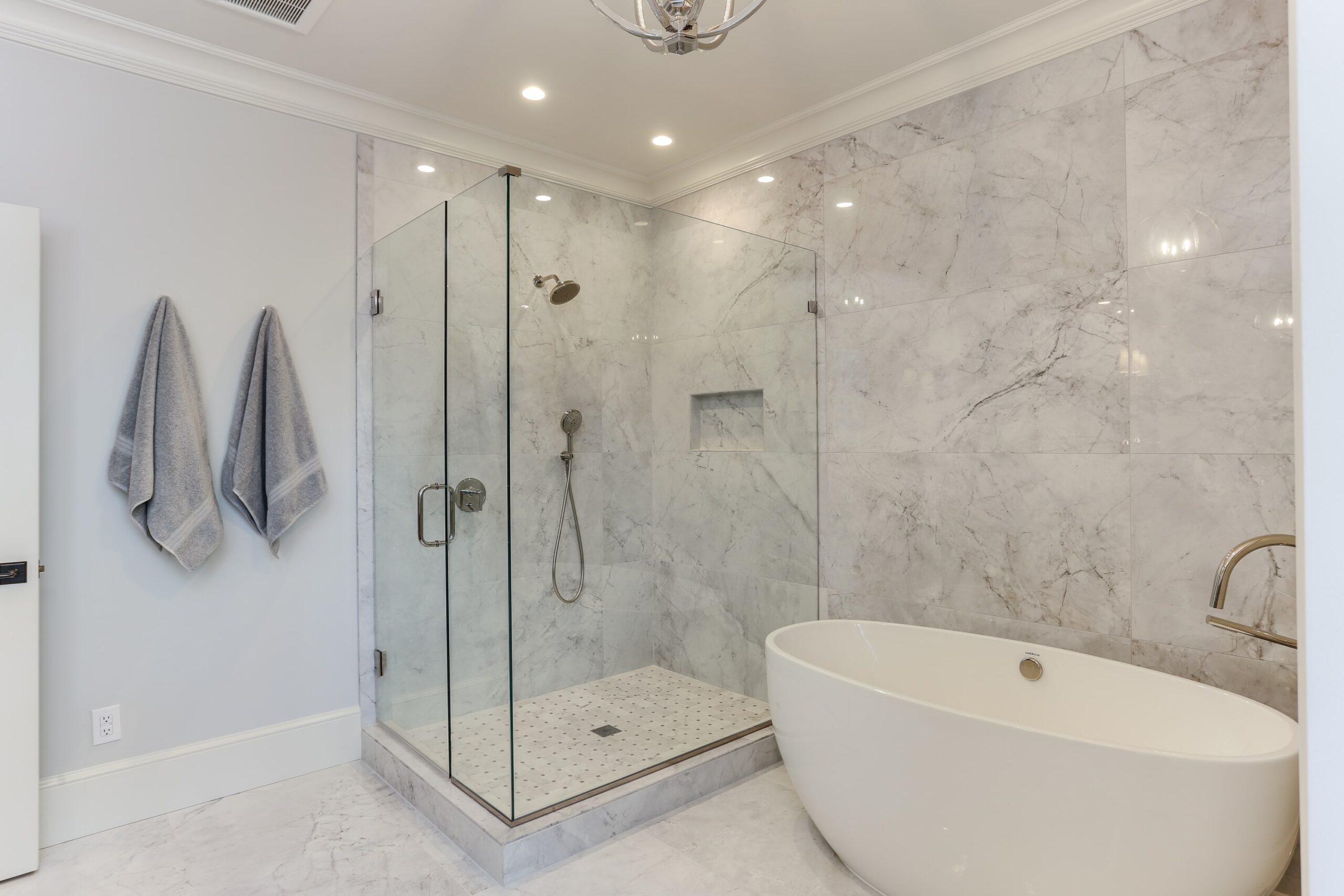 gray bathroom with a glass shower and stand alone tub